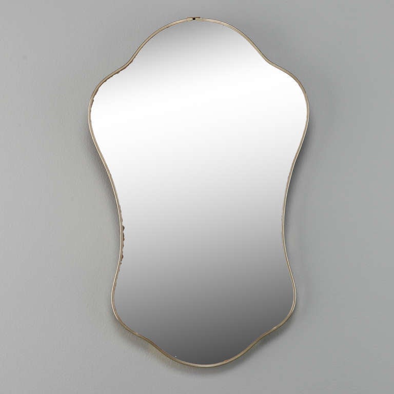 Small circa 1950s midcentury Italian brass framed mirror in a rounded, shield form in the manner of Gio Ponti.