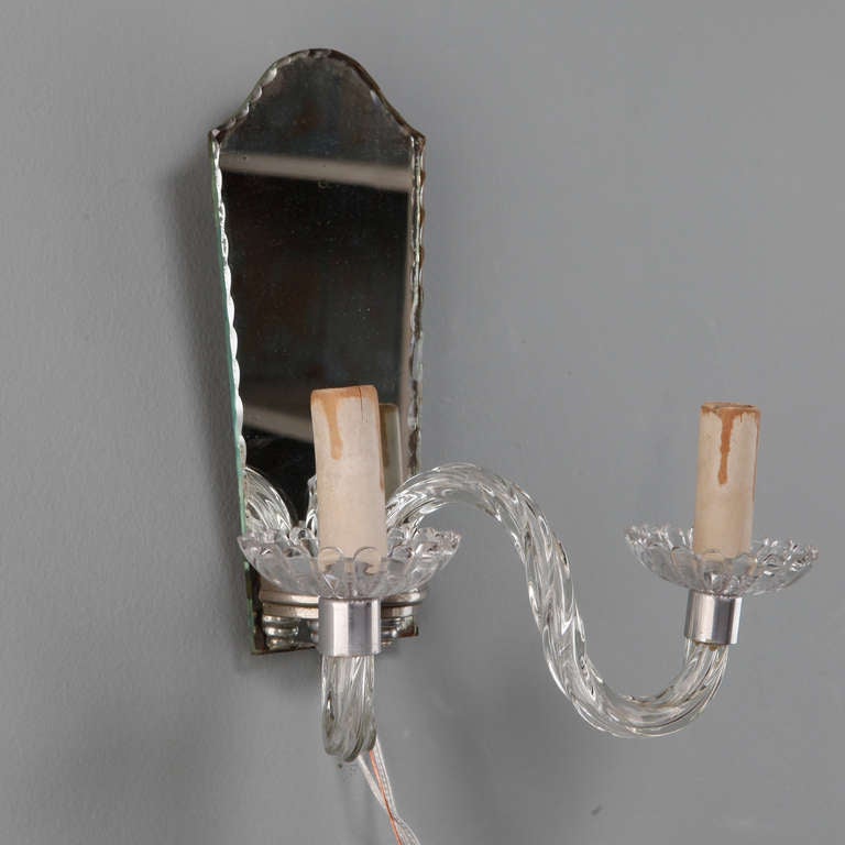 This pair of circa 1940s French sconces have arched mirror back, silver tone metal, two clear glass arms with a twisted ribbed surface, glass bobeches and candle style lights. New electrical wiring for US standards. Sold and priced as a