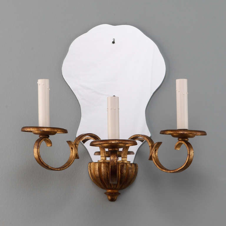 Circa 1920s French sconces have a gildwood base, three gilt metal arms with candle style lights and shield shaped mirror back plates. New wiring for US electrical standards. Sold and priced as a pair.