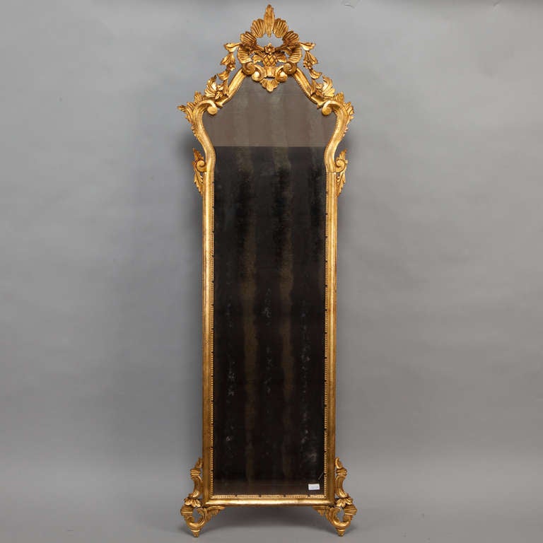 Circa 1780 tall, narrow Louis XVI gilded mirror with elaborate, open-work foliate crest.
