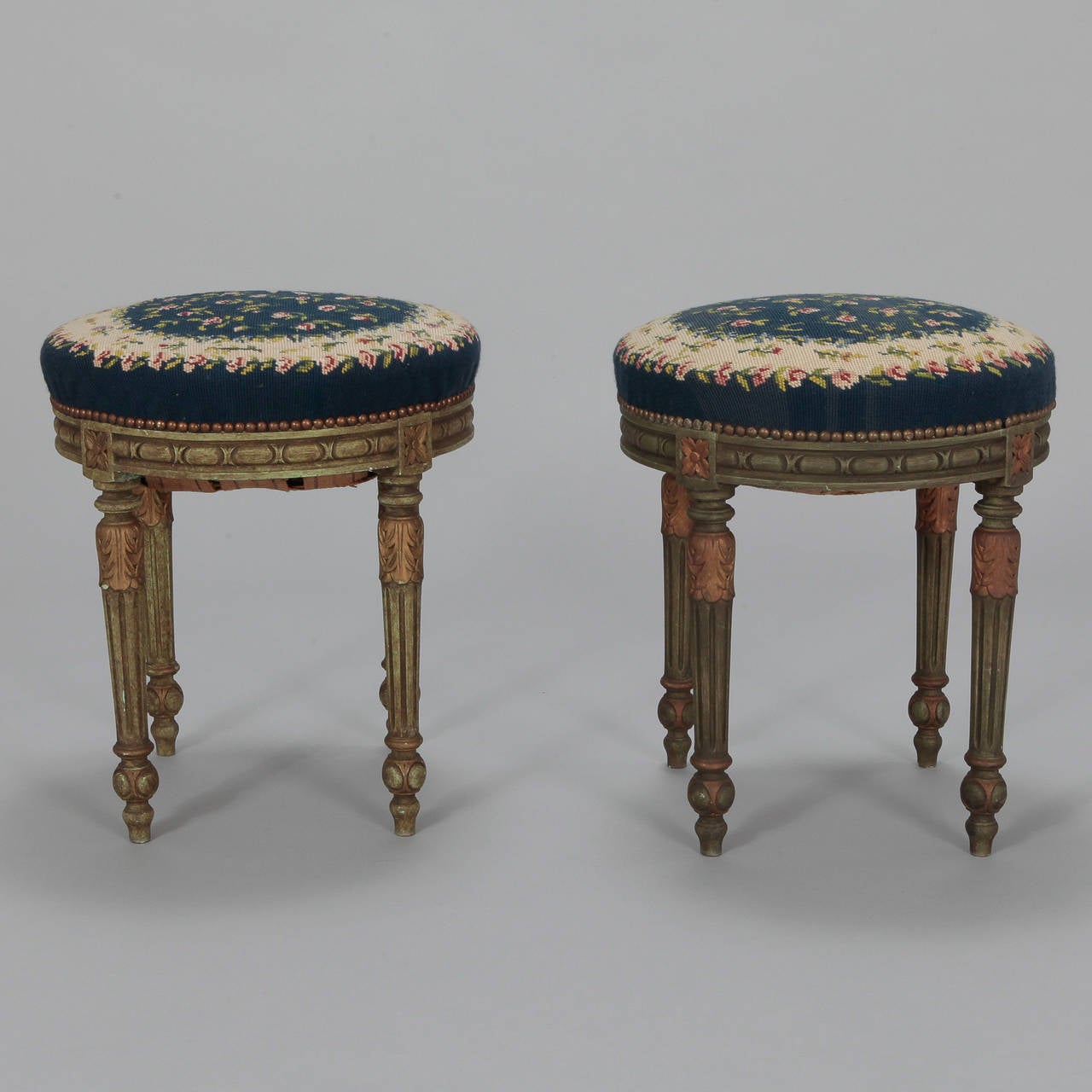 Pair of round French stools with reeded and tapered legs with green painted finish, circa 1920s. Covered in blue and cream needlepoint floral fabric. Sold and priced as a pair.