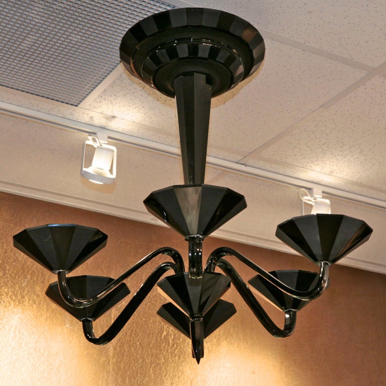 Outstanding Deco-era Murano glass chandelier in black. Faceted surfaces of harlequin glass - alternating panels of frosted/shiny glass. Six lights, curved arms, spire at bottom, faceted stem and stepped ceiling mount.
# of Sockets: 6
Socket Type: