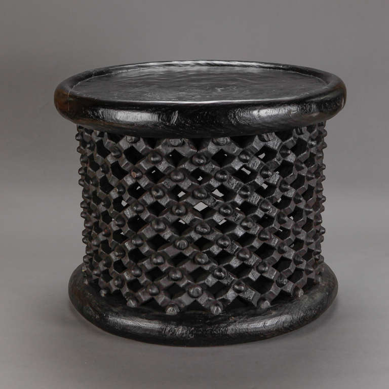 This dark stained round wood table was hand crafted by an artisan of Africa’s Bameleke tribe from Cameroon. This spider style table features a hand carved open work lattice design.  Use this as a side table or stool. Similar styles in various sizes