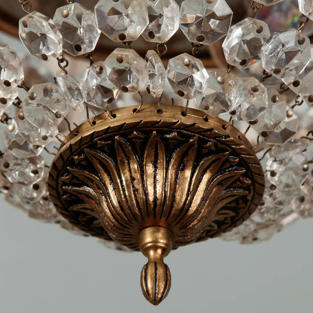 Pair of circa 1930s brass and crystal flush mount light fixtures. Found in France, these fixtures have a decorative dark brass frame and rim that supports faceted crystals strung in basket shape. New wiring for US electrical standards. Sold and