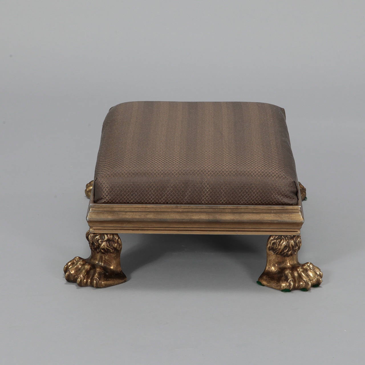 This foot stool is a real statement piece made with salvaged 19th century heavy cast brass, beautifully rendered lion paw feet. New upholstery.