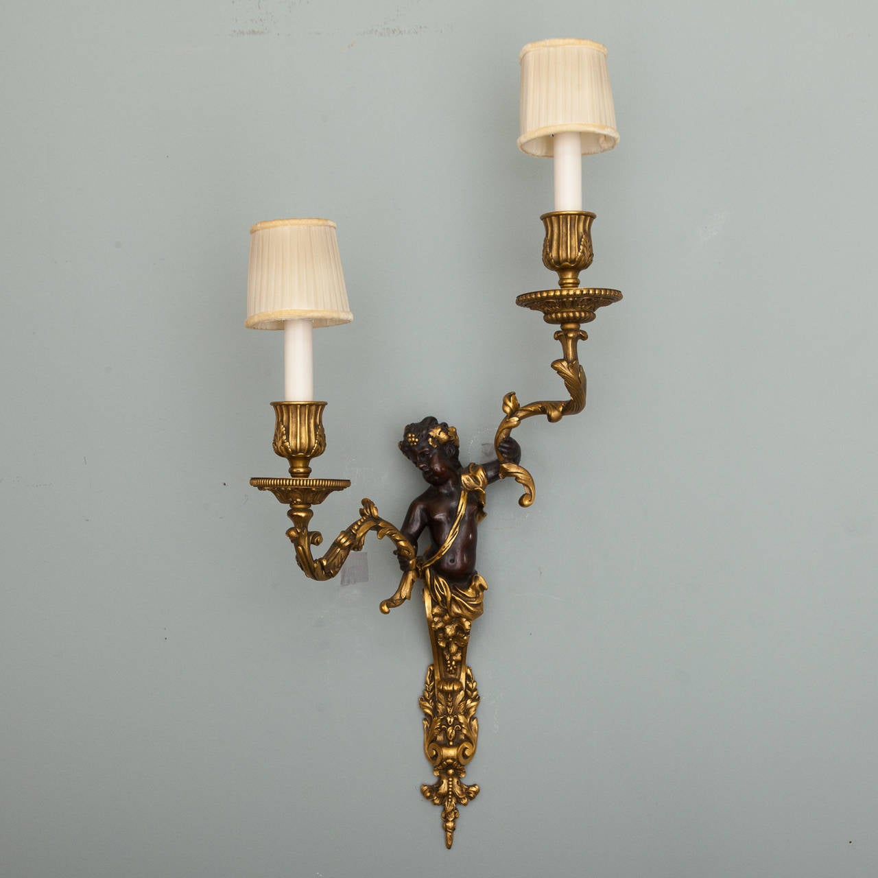 Circa 1900 pair of European bronze sconces with dark bronze puti and gilded bronze candle arms. New wiring for US electrical standards.