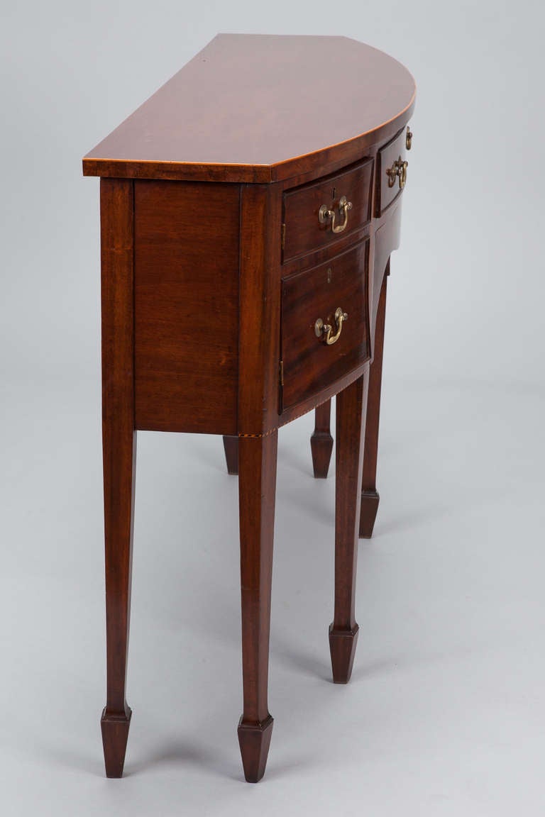 Circa 1870s English mahogany console has bow front with five drawers, brass hardware, curved apron and six tapered legs. The original dimensions of this piece have been customized; the depth has been reduced.