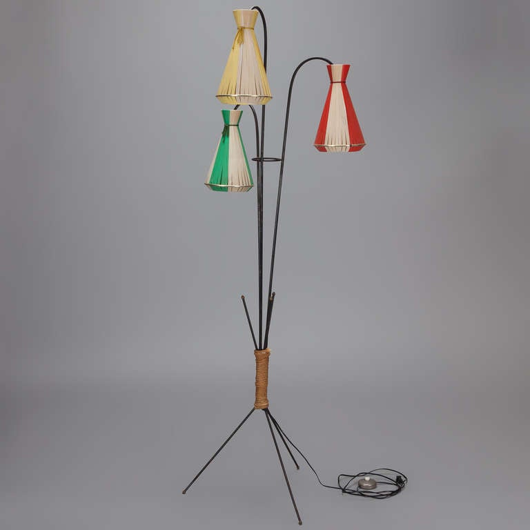Circa 1950s wrought iron floor lamp has tripod base wrapped in rattan and three lights with colored shades. New wiring for US electrical standards.