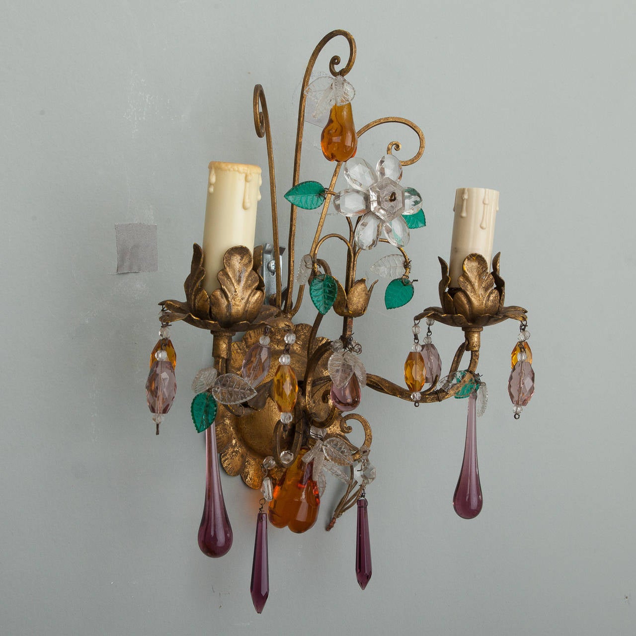 Circa 1940s pair of two light Italian tole sconces in gilt finish with candle style lights, colored crystal pendants and hand blown, glass fruit. New wiring for US electrical standards. Sold and priced as a pair.