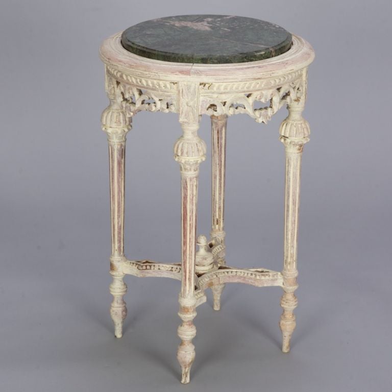 This highly carved French table has an off-white finish and green marble table top.
