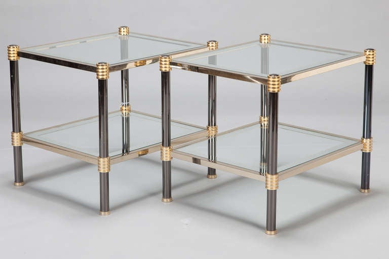 This mid century pair of side tables date from the 1960s and have two glass tiers, chrome frames with brass accents and black enamel legs. Sold and priced as a pair.
