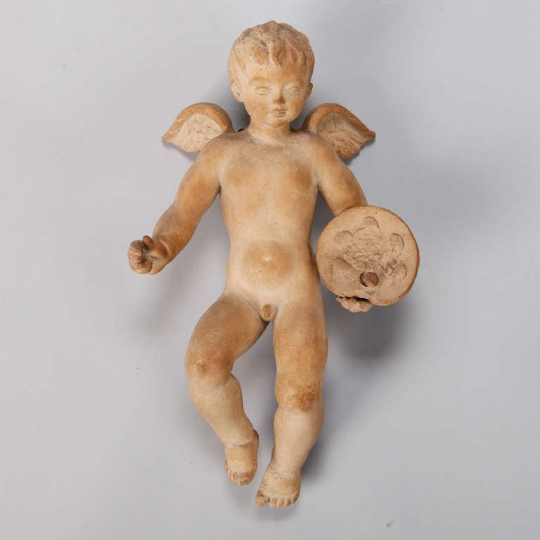 Beautifully sculpted large terra cotta cherub with painter’s palette. Signed by the artist on back of leg, but signature is difficult to read. Found in Belgium.