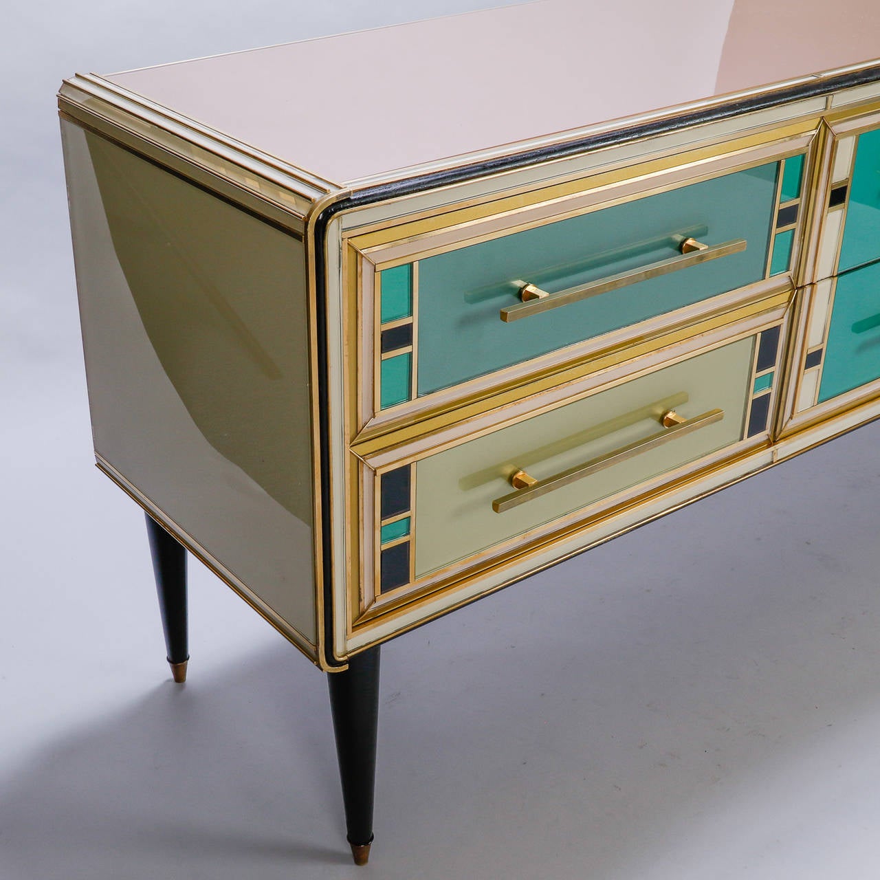 This circa 1990s sideboard has a black painted wood base with tapered legs, polished brass hardware and multicolored Murano glass panel overlays. Simply stunning. This is attributed to one of the early collections designer Emanuel Ungaro created for