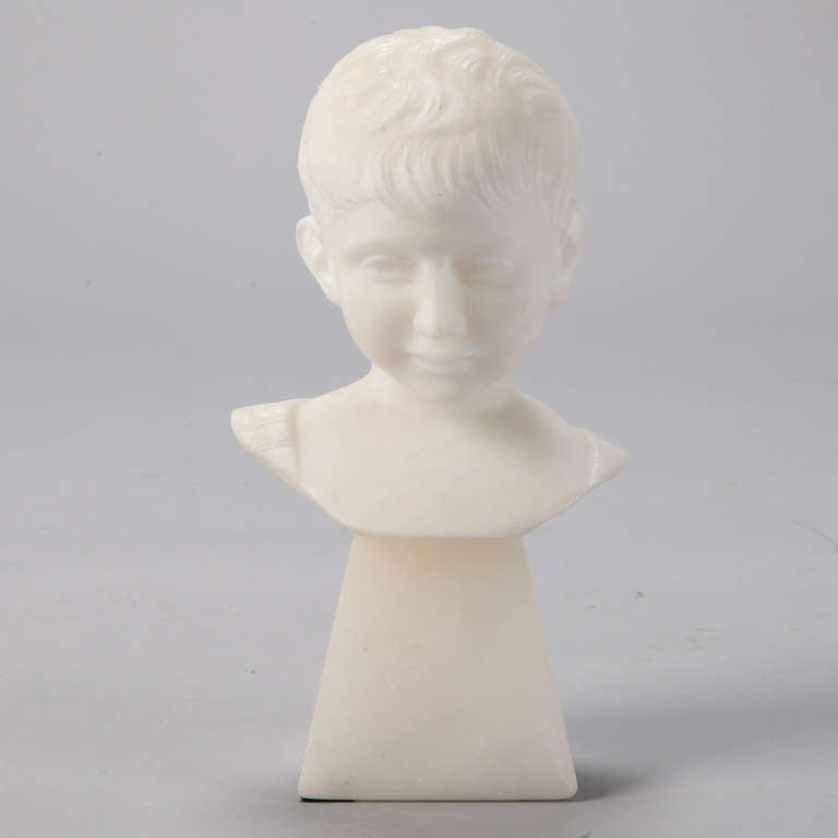 Beautifully detailed sculpted bust of a young boy rendered in pale white marble.