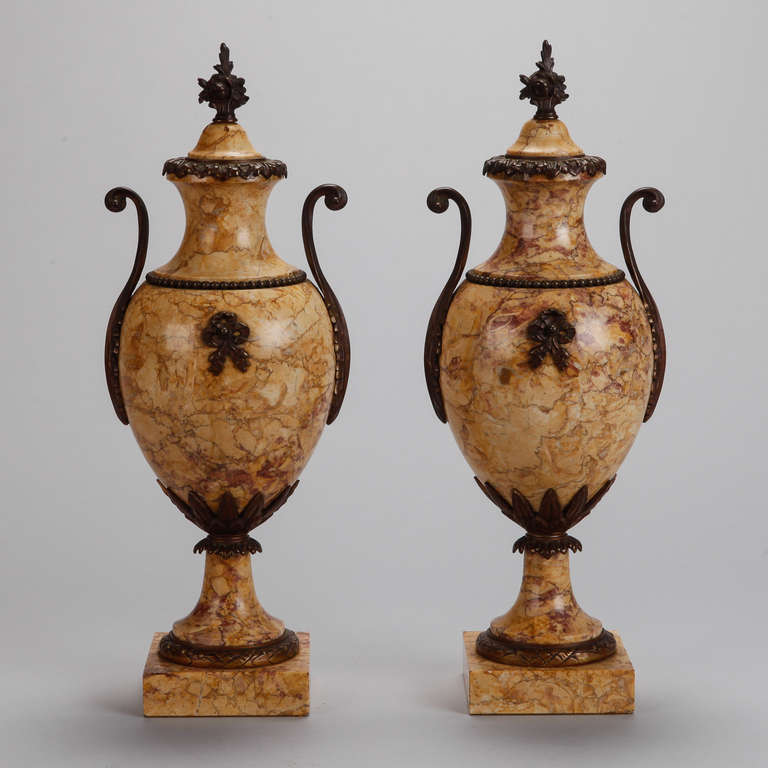 Circa 1930s pair tall French dark gold marble urns in classic amphora form with pedestal base and dark bronze decorative mounts. Missing ornament from back of vessel of one urn. Sold and priced as a pair.