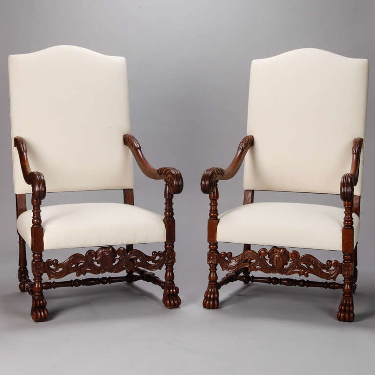 Circa 1880 pair of French walnut throne style chairs with upholstered seats and high backs. Elaborately carved aprons, legs and beautifully scrolled arms. Newly upholstered in muslin and ready for the fabric of your choice. Seats are 16