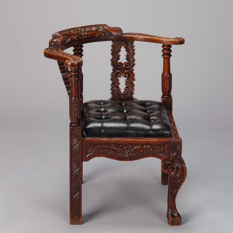 19th century English corner chair with elaborately carved frame and black leather tufted seat. Arm height is 28.75