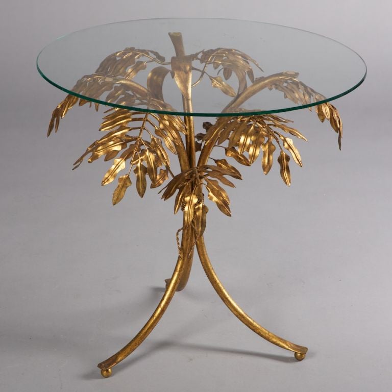 Circa 1960 side table by Italian design house Fornasetti has a three leg brass base of sculpted fern leaves, and round glass top.