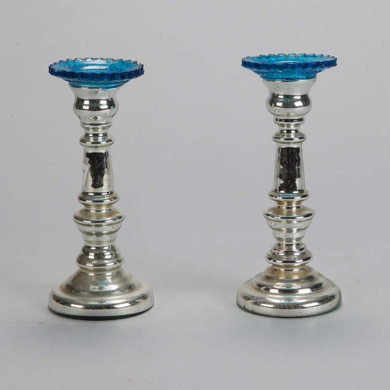 Circa 1890s mercury glass candlesticks with blue glass bobeches. Sold and priced as a pair.