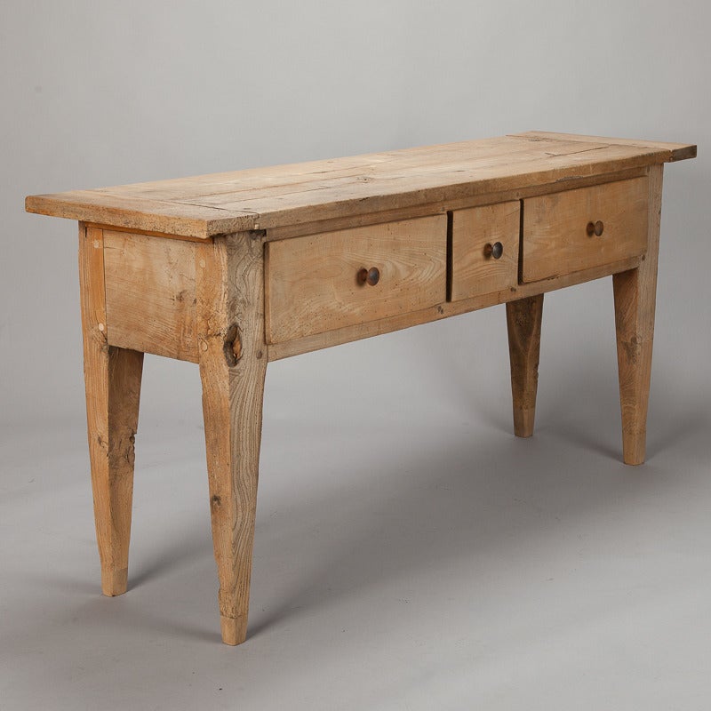 Circa 1840s three drawer server has a base of bleached elm with a bleached and aged apple wood top. Tapered legs, functional drawers.  Use this piece as a console or server.  Found in France. 

31.5” High X 65.5” Wide X 19” Deep

Retail $4295