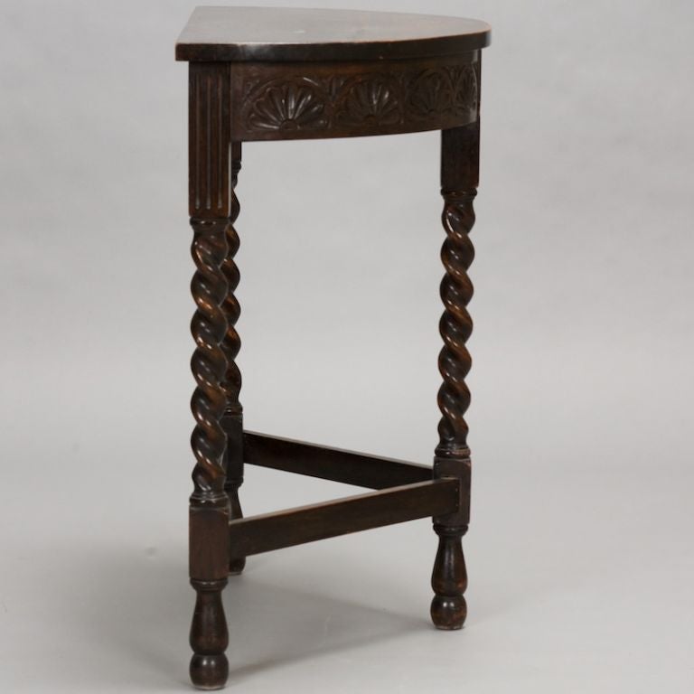 This oak demilune table has a carved apron, barley twist legs, and turned feet.
