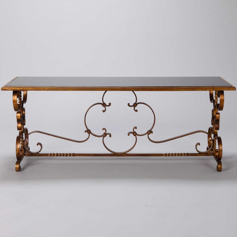 Italian low cocktail or coffee table with gilded iron base, scrolled feet and black glass tabletop, circa 1930s.