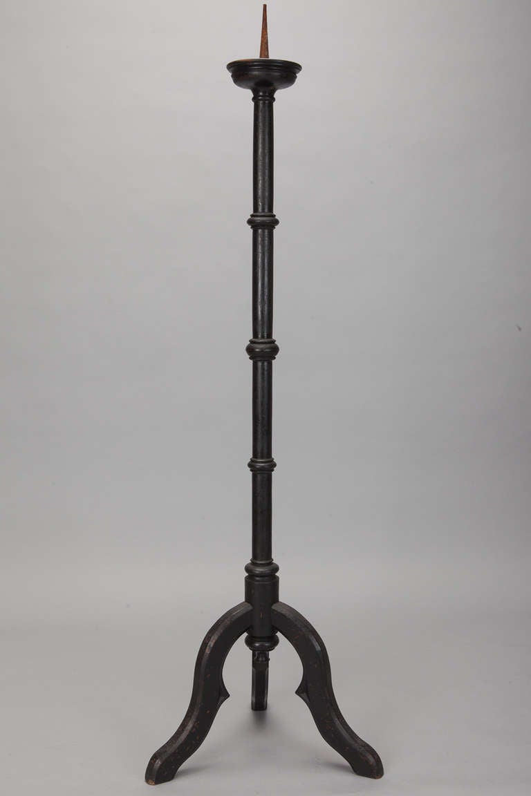 Monumental standing wood black pricket stick is five feet tall with a trifooted base and turned center column with decorative round spacers. Six total available - sold and priced individually.