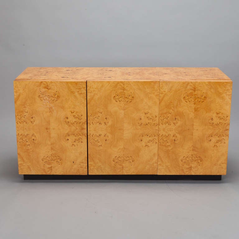Circa 1970s credenza / buffet designed by Milo Baughman for Thayer Coggin has three hinged cabinet doors, internal shelves and a pull out drawer. Polished blond olive burl  wood veneer.
