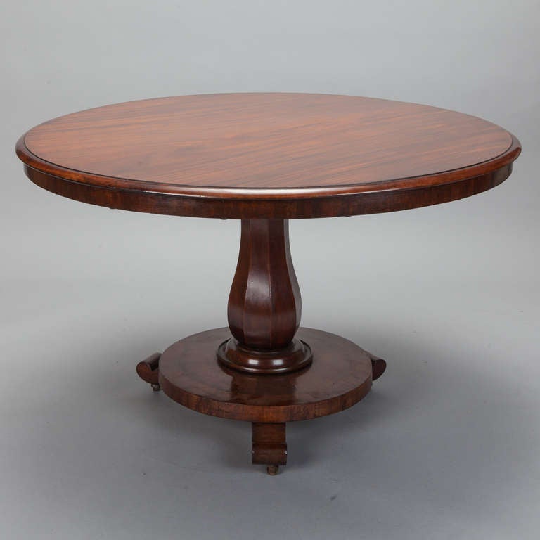 Circa 1870s round center or breakfast table with a tilt top in beautifully grained mahogany and a pedestal base with scrolled feet.