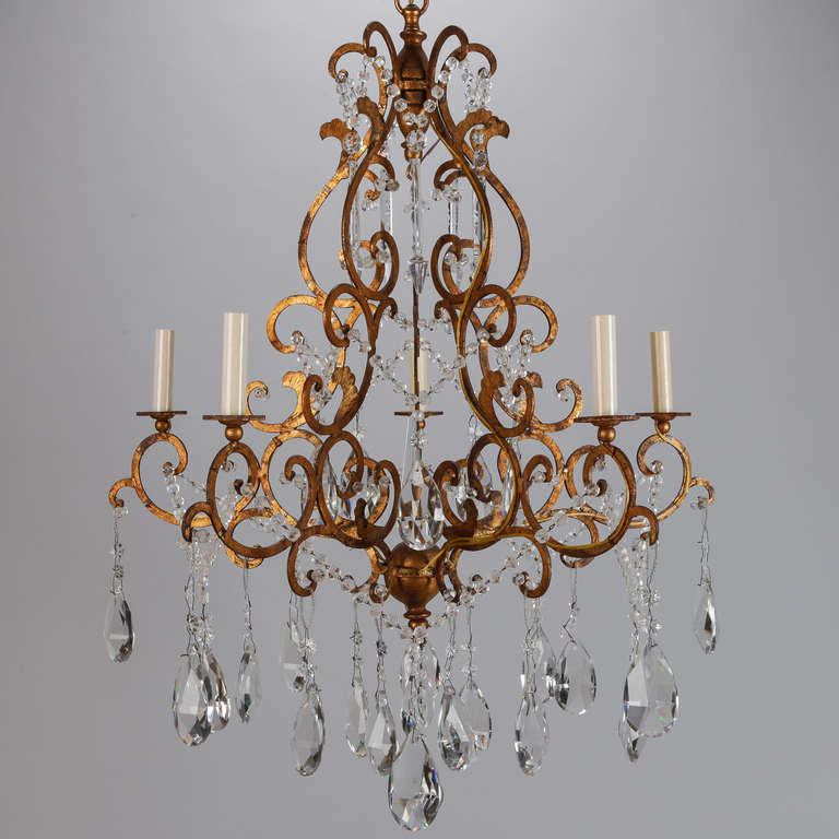 Circa 1930s Italian chandelier with gilded and scrolled metal frame and six candle style lights. Chandelier has a large center crystal ball drop, several large, clear faceted pear shaped crystals, strings of glass beads, flower shaped crystals and