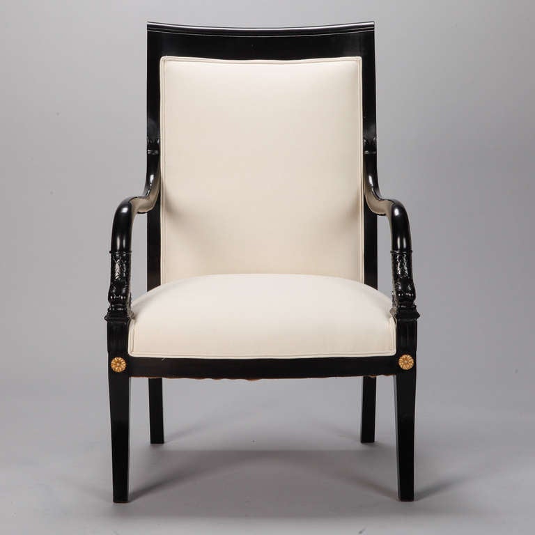 Late 19th century pair of upholstered his and hers chairs. Frames are made of ebonized mahogany with carved dolphin-form arms and decorative brass medallion mounts. Newly upholstered in muslin and ready for the fabric of your choice. Measurements
