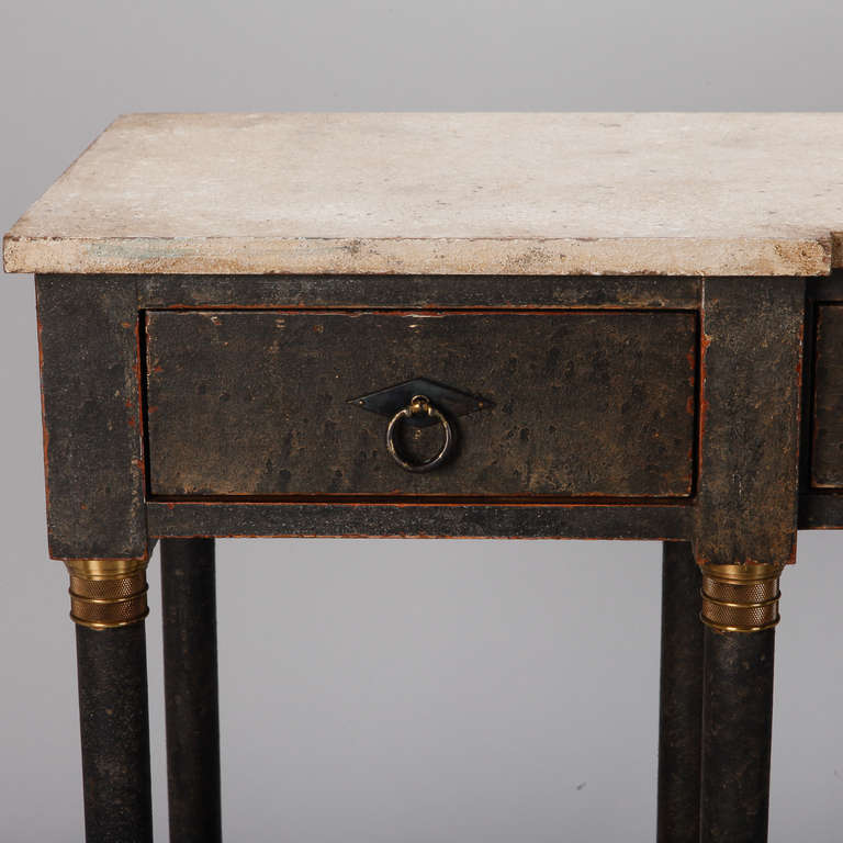Circa 1920s eight leg console with black painted finish, brass details, three narrow functional drawers and a white faux painted marble top.