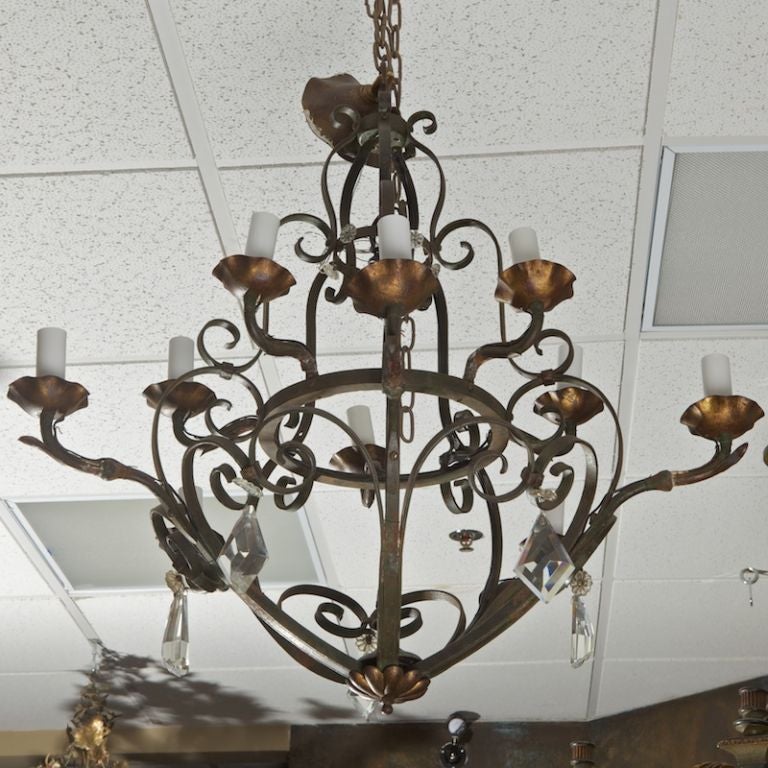 This French hand-forged metal ten-light chandelier has a bowl shaped base with two tiers of five candle style lights, curved iron arms, contrasting copper tone candle cups and large, faceted crystal pendant drops, circa 1930s.
# of Sockets: