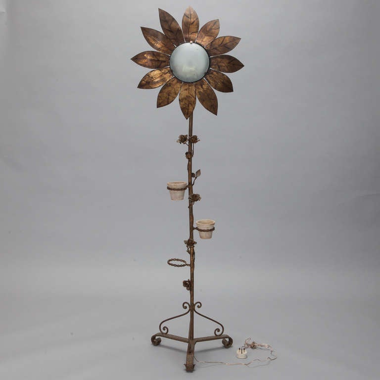 Circa 1930s tall gilt metal Spanish floor lamp in the form of a sunflower with a scrolled, trifoot iron base,  illuminated white glass center and three flower pot holders on center support. New wiring for US electrical standards.