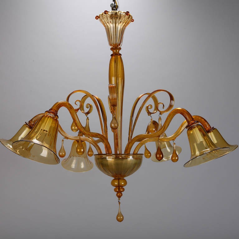 Stunning, circa 1920s amber colored Murano glass chandelier attributed to Venini. The fixture has six lights, decorative scrolled elements with teardrop shaped glass pendants and bell shaped globes. Central shaft and ceiling mount of handblown