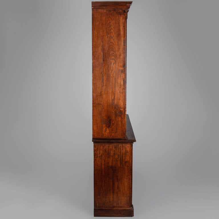 Circa 1850s English bookcase made of oak with classic square front, fluted column supports. Base has two sections with single shelf, top section has two adjustable shelves on each side.