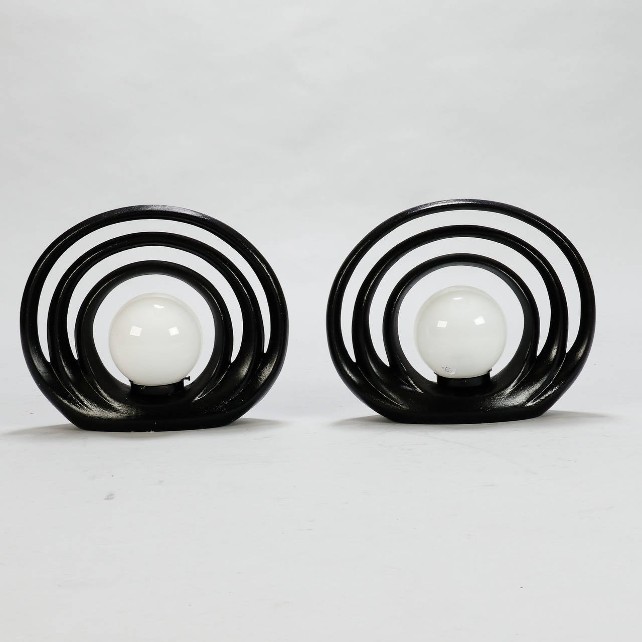 Pair circa 1970s Italian mod Op Art table lamps with three black ceramic concentric circles with a white glass globe in the center. New wiring for US electrical standards. Sold and priced as a pair. Excellent vintage condition with no flaws found.