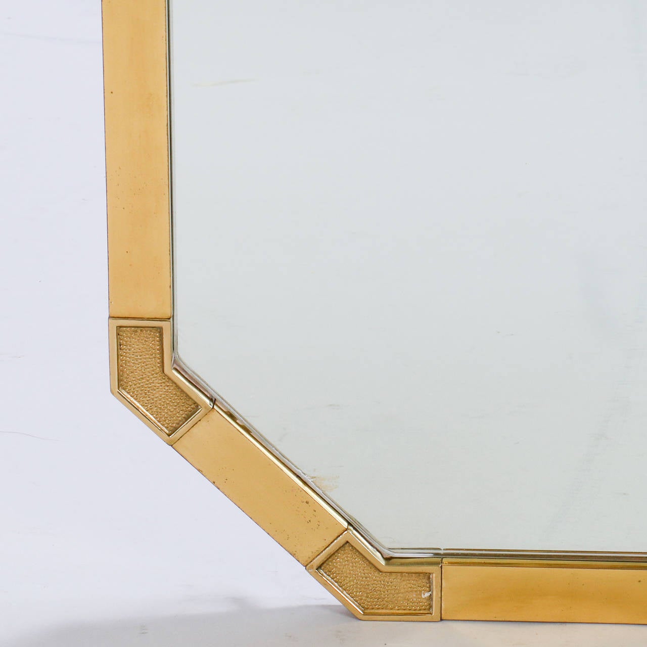 Found in Italy, this circa 1960s large rectangular mirror has a flat, brass frame with textured surface details at the angled corners.