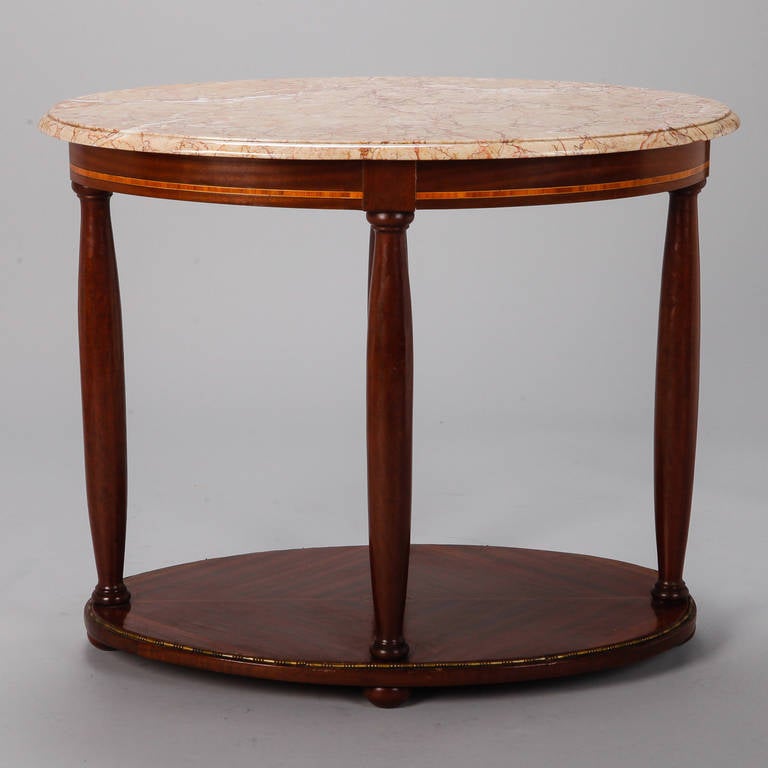 Directoire style centre table with oval marble top in pale rouge shade supported by tapered wood columns and oval base, circa 1900.