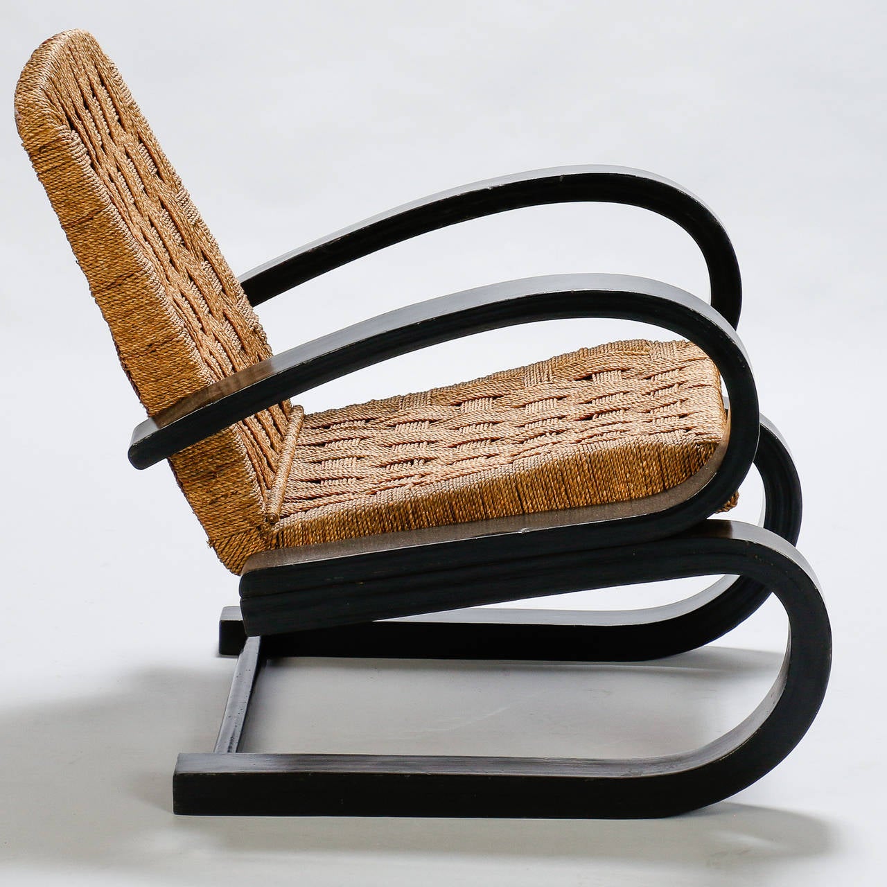 Armchair found in Italy with double form dark bent wood arms and woven rush seat and back in the manner of Audoux Minet, circa 1950s.  Seat is 16.5” high and 19.5” deep. Arms are 23.75