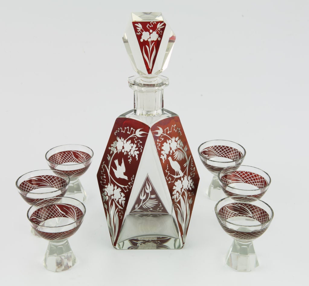 Attributed to Karl Palda for Haida, this Art Deco decanter set features a glass decanter with stopper in clear and red glass etched with birds and flowers and six matching footed glasses. Makes a beautiful gift! Measurements shown are for the