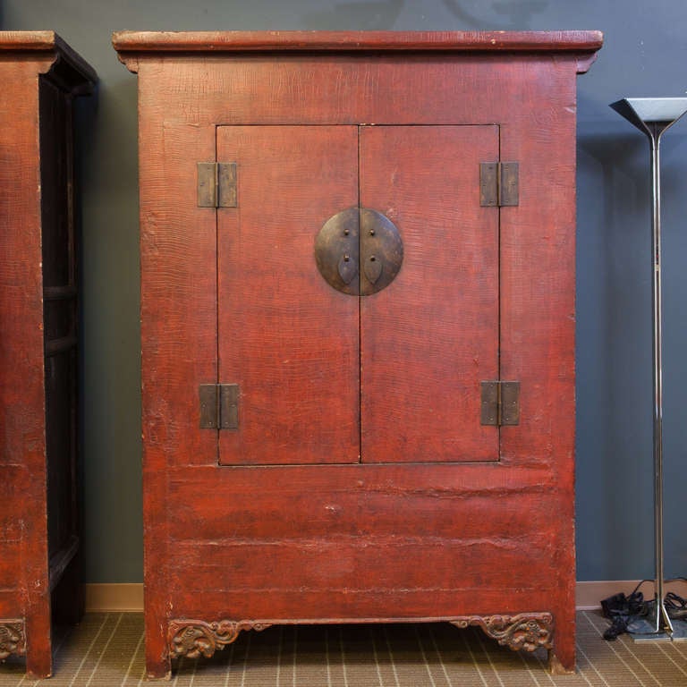 Large Chinese wood cabinet with red lacquer finish, brass hardware, hinged front doors and two internal drawers, circa 1900.