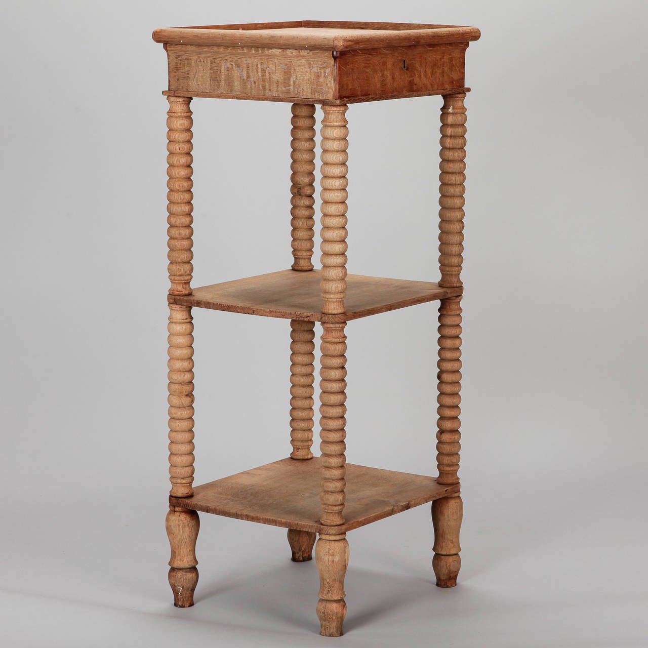 Bleached oak two tier small display table or étagère found in France. Turned bobbin style legs with two lower shelves and single, functional shallow drawer, circa 1900.
