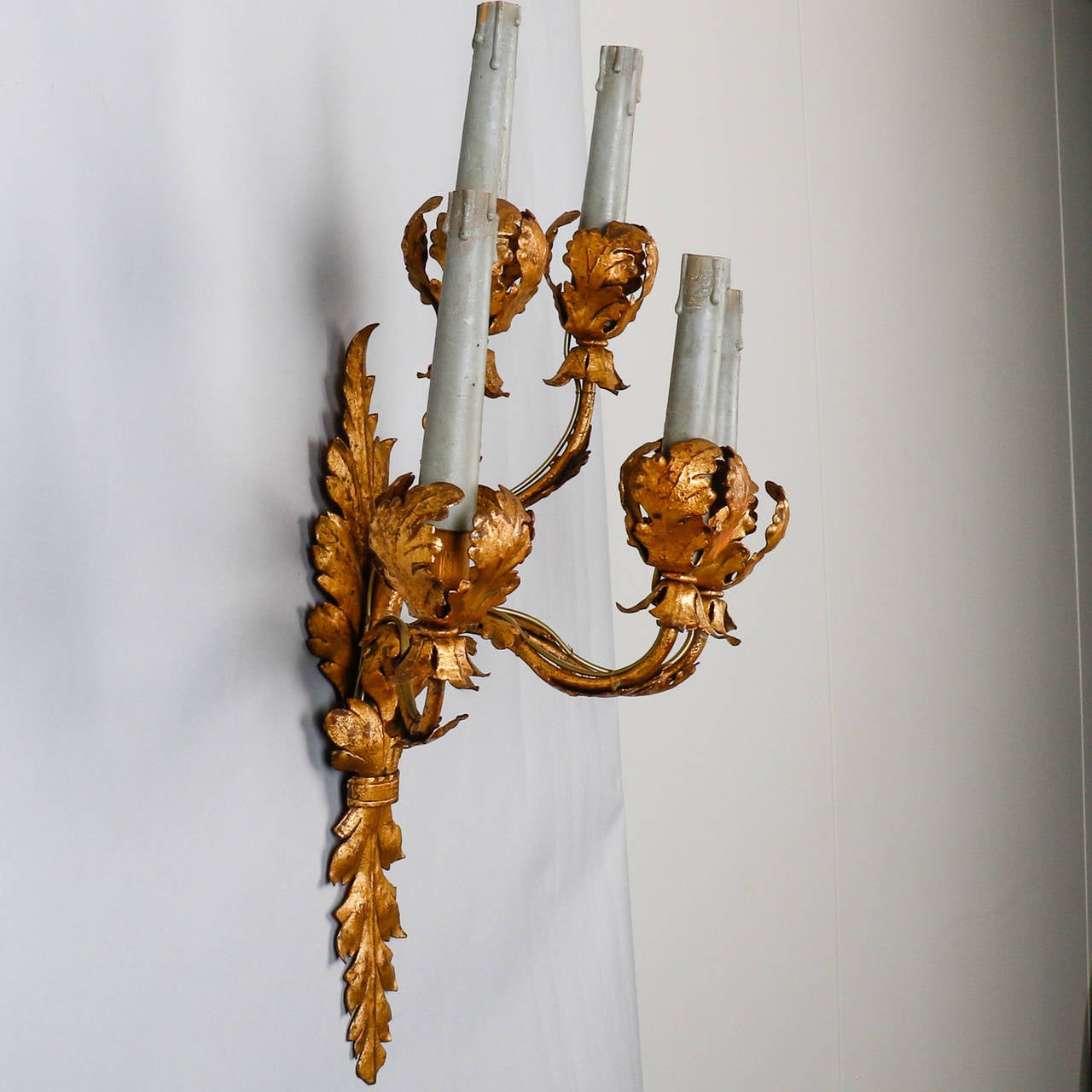 Pair of circa 1930s electrified sconces of gilded metal with leaf form design and five candle style lights. Sold and priced as a pair. Two pairs currently available. New electrical wiring for US standards. Bulbs: 60 watt candelabra base.