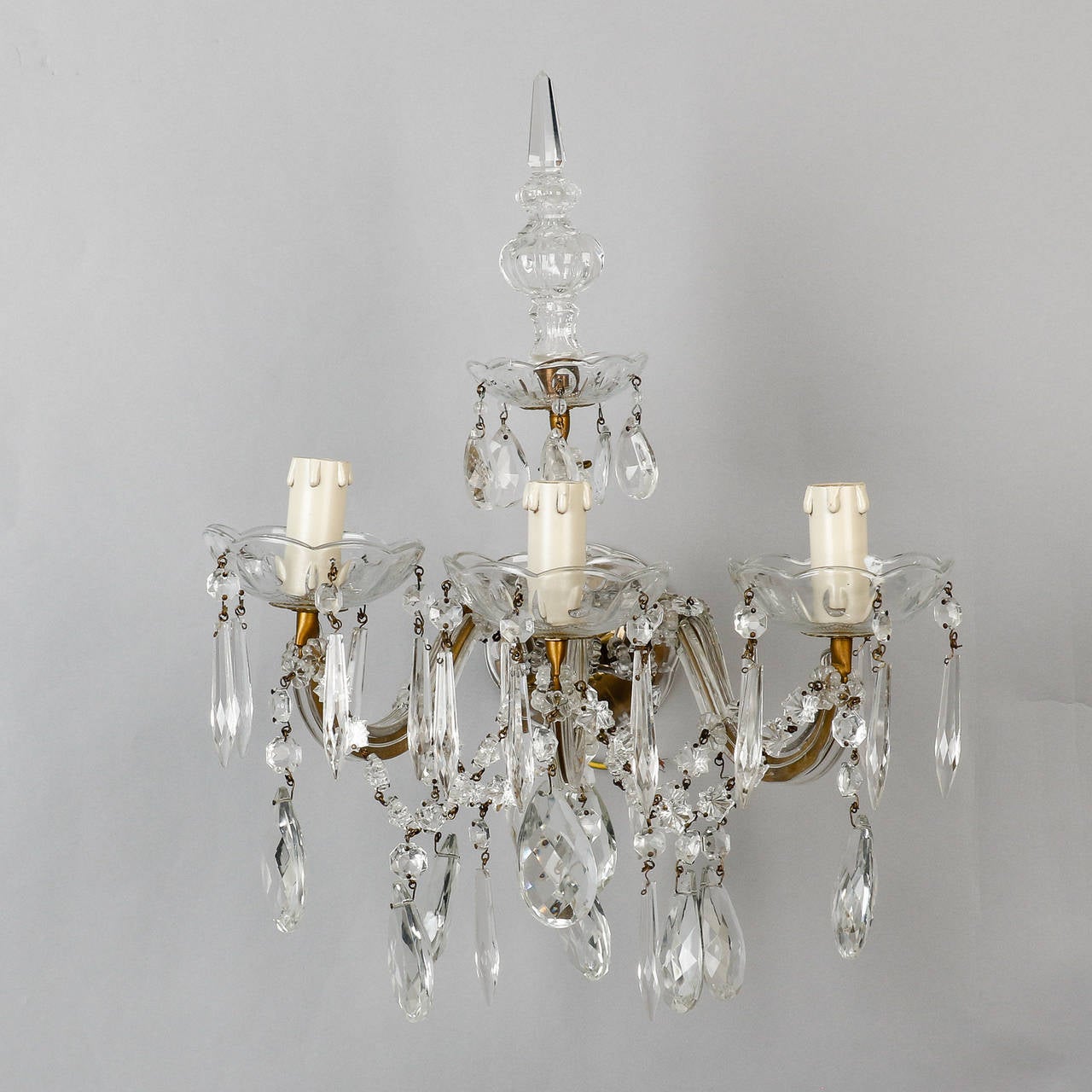 Found in Italy, this pair of elaborate Maria Theresa style three light sconces date from 1920s. Each sconce has three candle style lights, glass bobeches, many crystal pendants and tall, crystal spire finials. Sold and priced as a pair. New wiring