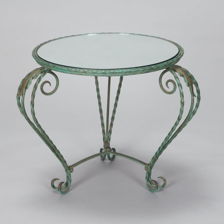 Italian occasional table has twisted wrought iron frame with green finish, scrolled supports and feet, round mirrored glass top, circa 1930s. Top is 19