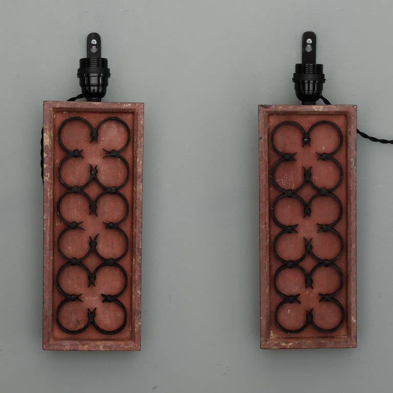 Pair of sconces or wall appliques feature a base made from decorative architectural elements. Painted wood frames a row of three iron quatrefoils. New wiring for US electrical standards. Sold and priced as a pair.