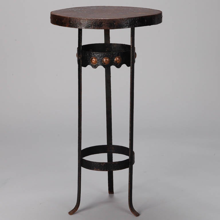 Small bronze gueridon side table is supported on three feet, has polished brass embellishments on the top spreader and round forms in relief around the apron, circa 1930s. Visible patina to table top and base.