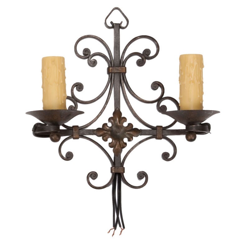 These two light iron wall sconces feature fancy scrolled back plates. Sold and priced as a pair.