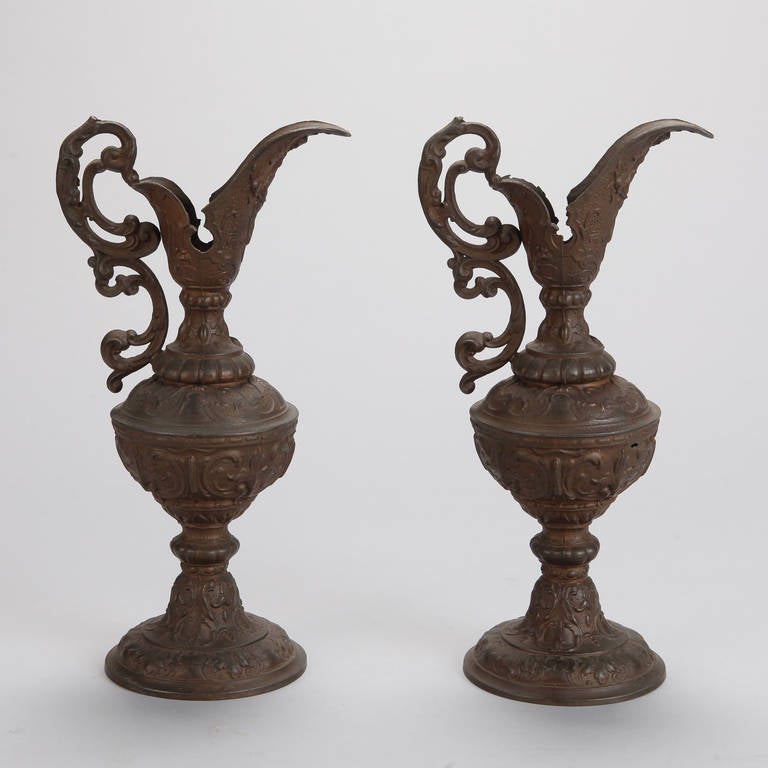 Circa 1910 pair of tall European bronze ewers with fancy, double scrolled handles, pedestal base and round body. Sold and priced as a pair.